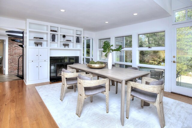 dining room with a fireplace with flush hearth, light wood-style flooring, and recessed lighting