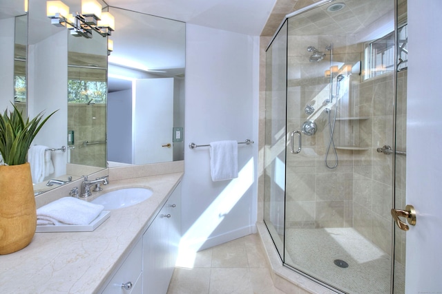 bathroom with a shower stall, tile patterned flooring, vanity, and a chandelier
