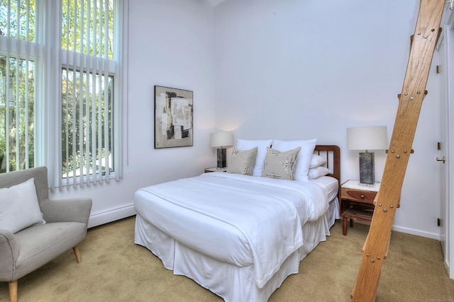 bedroom with light carpet, baseboards, and a baseboard heating unit