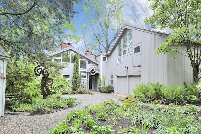 view of front of home featuring an attached garage, a chimney, and driveway