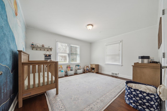 bedroom featuring wood finished floors, visible vents, crown molding, and baseboards