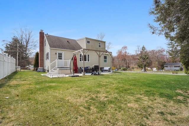 rear view of property with a yard, a shingled roof, a chimney, and fence