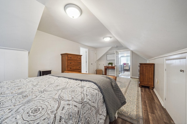 bedroom with vaulted ceiling, wood finished floors, and baseboards
