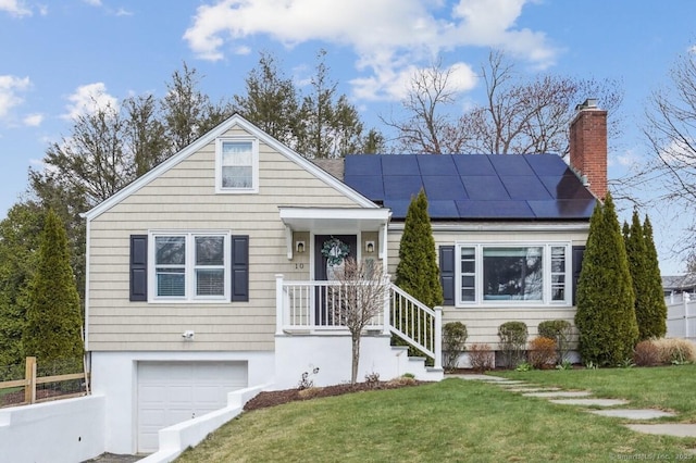 view of front facade featuring a chimney, solar panels, a front yard, and a garage
