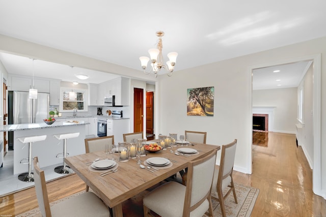 17 Lydall Rd, East Hartford, CT 06111 - dining area featuring a chandelier, a fireplace, light wood-style floors, and baseboards