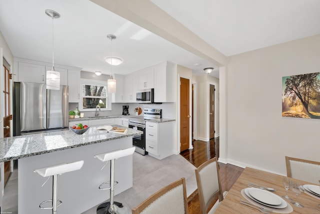 17 Lydall Rd, East Hartford, CT 06111 - kitchen with appliances with stainless steel finishes, a sink, white cabinetry, decorative backsplash, and light stone countertops
