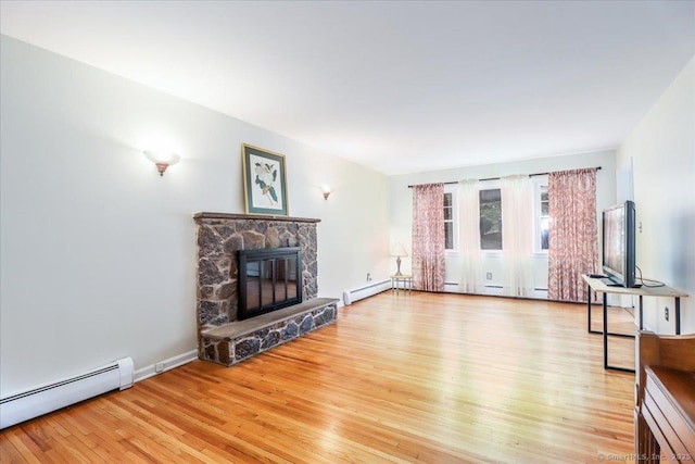 unfurnished living room with baseboard heating, baseboards, a stone fireplace, and light wood finished floors