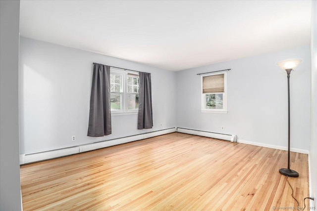 spare room with a baseboard radiator, baseboards, and wood finished floors