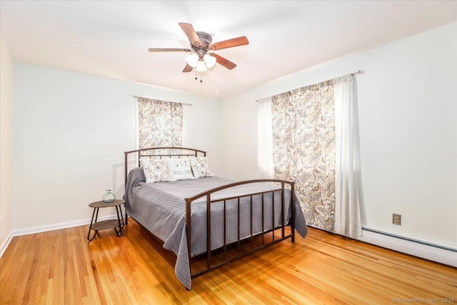 bedroom with baseboards, baseboard heating, wood finished floors, and a ceiling fan