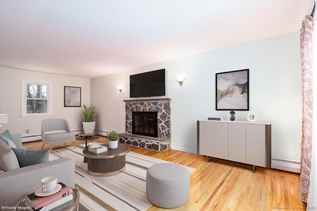 living room featuring wood finished floors, baseboard heating, and a stone fireplace