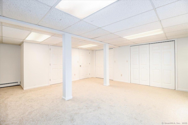 finished below grade area with a paneled ceiling, baseboards, carpet floors, and a baseboard radiator