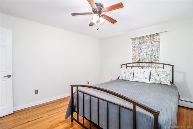 bedroom with ceiling fan, baseboard heating, wood finished floors, and baseboards