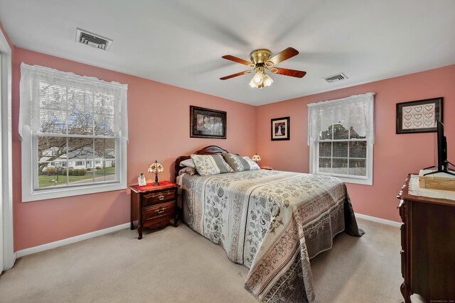 bedroom with light colored carpet, visible vents, and multiple windows