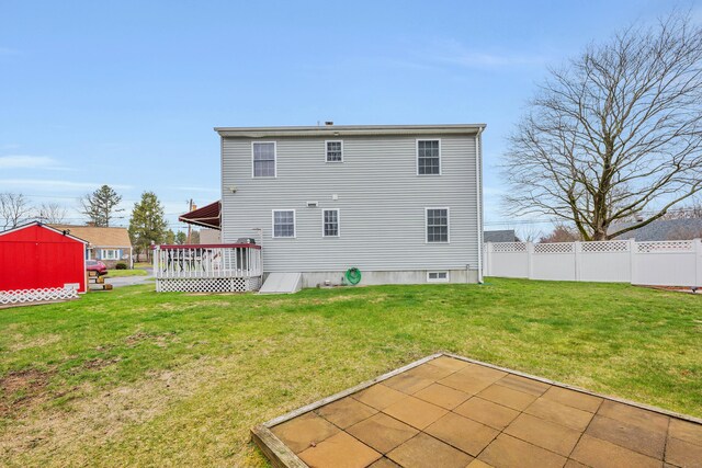 rear view of house featuring fence, a deck, and a lawn