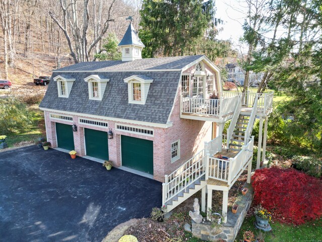 77 Main St, East Haddam, CT 06423 - view of home's exterior featuring stairway, brick siding, roof with shingles, a wooden deck, and a detached garage