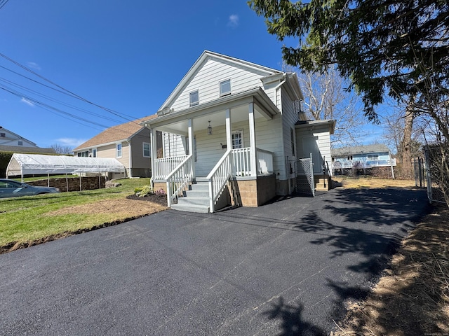 view of front of home featuring a porch, a front lawn, and aphalt driveway