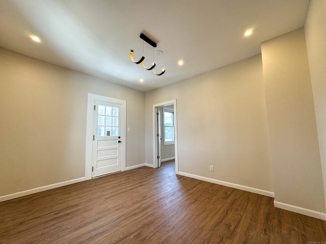 unfurnished room featuring baseboards, recessed lighting, a notable chandelier, and dark wood-style floors