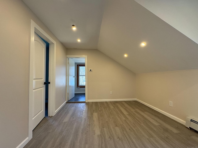 bonus room with dark wood-type flooring, baseboards, a baseboard heating unit, and lofted ceiling