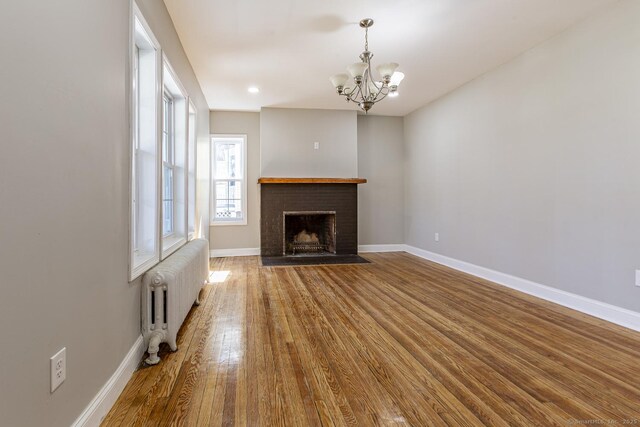67-69 Sterling St, Hartford, CT 06154 - unfurnished living room featuring baseboards, a chandelier, a fireplace, radiator, and wood finished floors