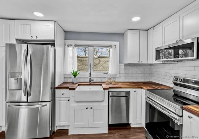 kitchen with wooden counters, a sink, backsplash, and stainless steel appliances