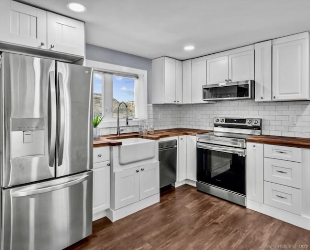kitchen with appliances with stainless steel finishes, wooden counters, white cabinets, and dark wood finished floors