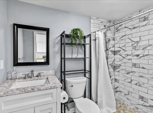 bathroom with a tile shower, toilet, and vanity