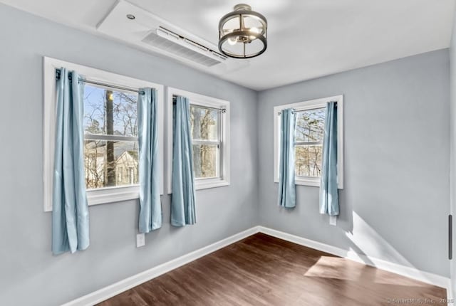 interior space with dark wood-type flooring, a notable chandelier, and baseboards
