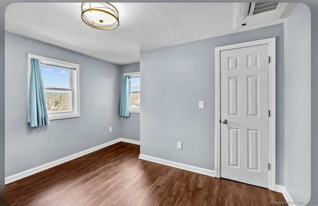 interior space with visible vents, multiple windows, wood finished floors, and baseboards