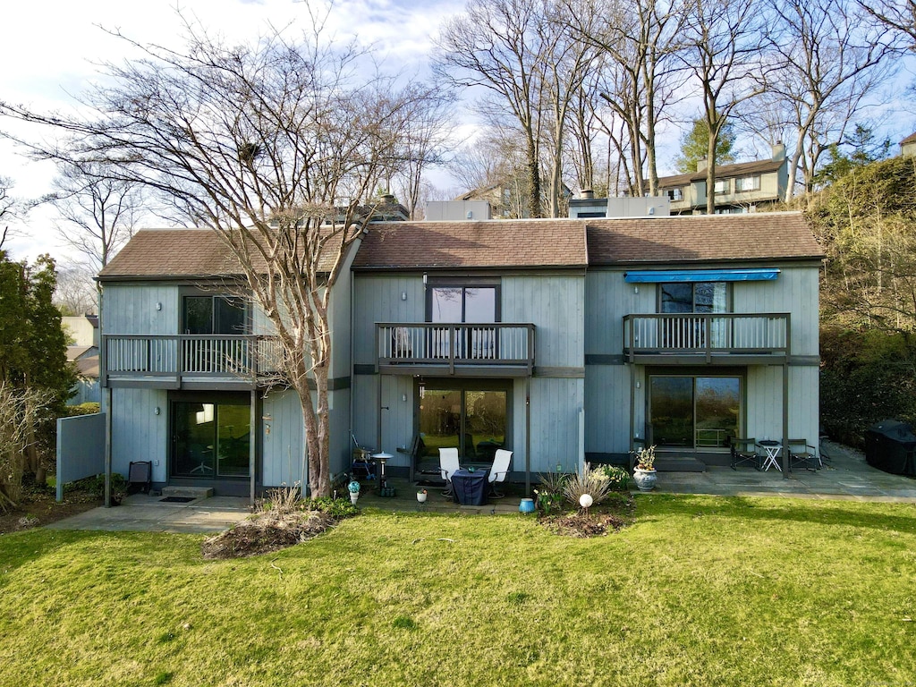 back of house featuring a balcony, a yard, and a patio area