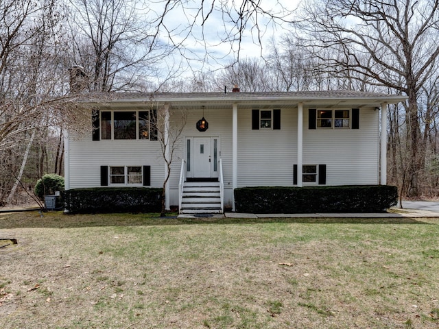 bi-level home with cooling unit, a chimney, and a front lawn