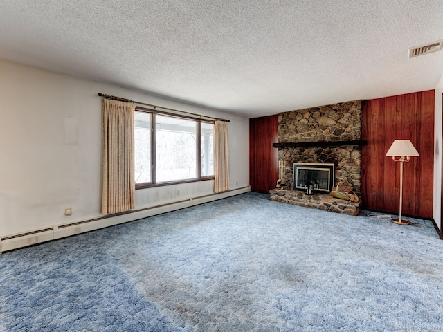 unfurnished living room featuring visible vents, a stone fireplace, a baseboard radiator, a textured ceiling, and carpet floors