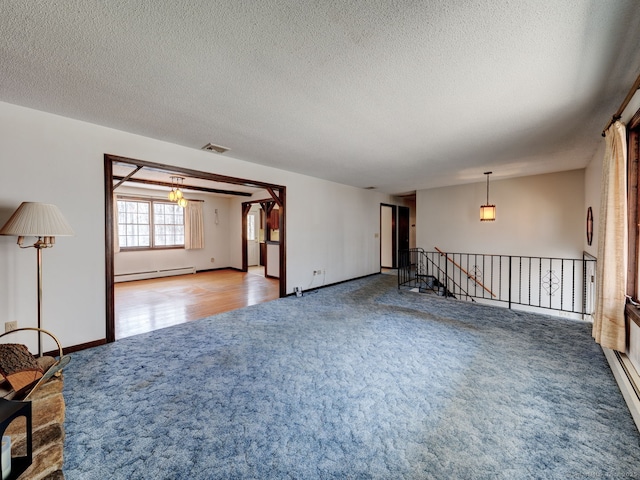 carpeted empty room with baseboards, visible vents, a baseboard heating unit, and a textured ceiling