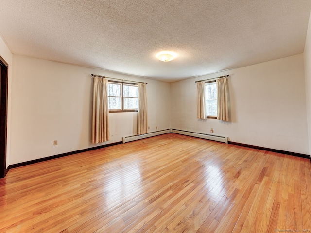 unfurnished room with light wood-style floors, a baseboard heating unit, baseboards, and a textured ceiling