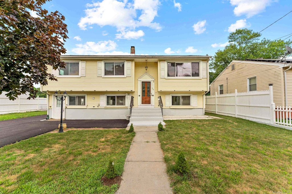 18 Jefferson Ln, East Hartford, CT 06118 - bi-level home with a front lawn, a chimney, fence, and driveway