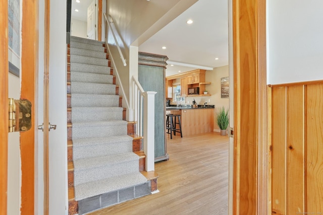 stairs with wood finished floors and recessed lighting