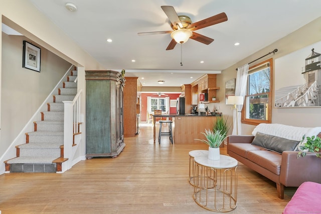 living room with light wood-type flooring, plenty of natural light, and ceiling fan