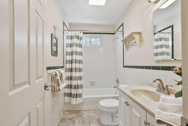 full bathroom featuring a wainscoted wall, toilet, tile walls, shower / bath combination with curtain, and vanity