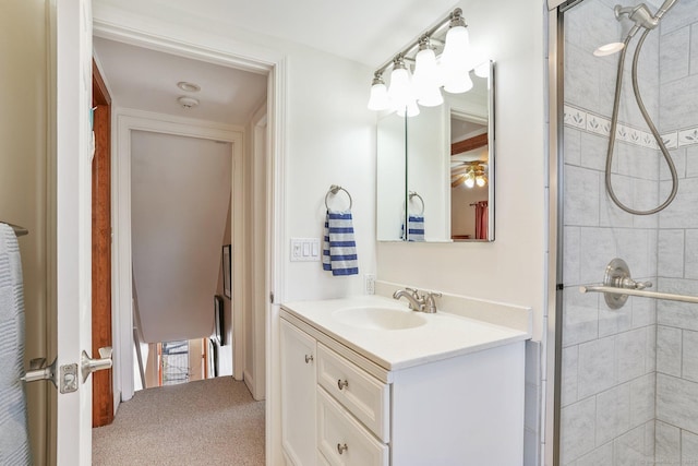 bathroom with a tile shower, vanity, and ceiling fan