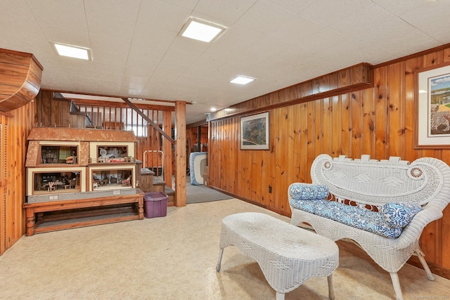 sitting room featuring wooden walls, carpet flooring, and stairs
