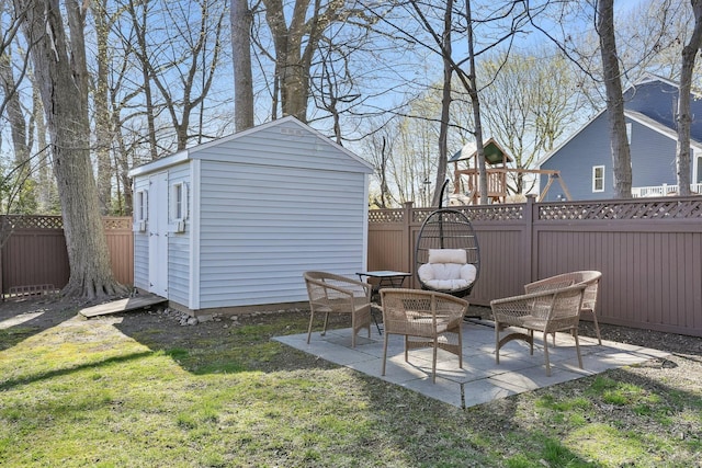 view of yard featuring a fenced backyard, a playground, a patio area, an outdoor structure, and a shed