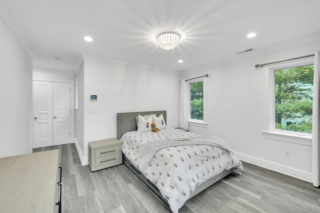 bedroom featuring light wood-style flooring, crown molding, baseboards, and multiple windows