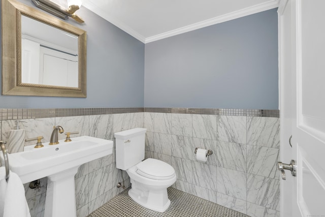 half bath with tile walls, toilet, crown molding, wainscoting, and tile patterned flooring
