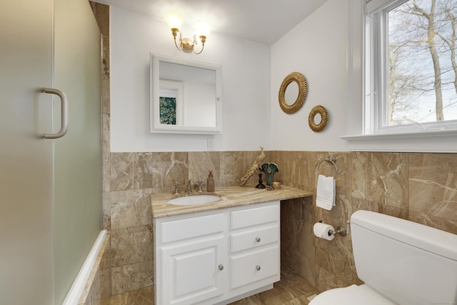 bathroom featuring tile walls, toilet, an enclosed shower, vanity, and a wainscoted wall