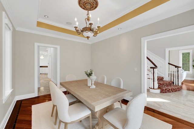 dining area with baseboards, a chandelier, stairway, a raised ceiling, and wood finished floors