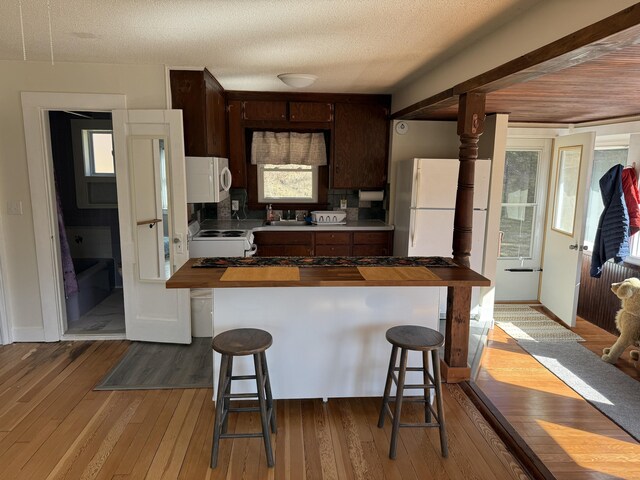 230 Old Field Rd, Southbury, CT 06488 - kitchen with white appliances, butcher block counters, dark brown cabinetry, a kitchen bar, and hardwood / wood-style flooring