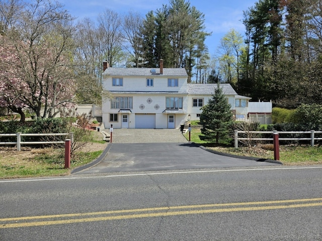 view of front of house featuring fence, a chimney, aphalt driveway, and a garage