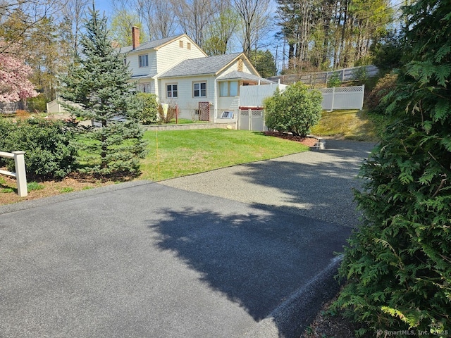 view of front of property with fence, a front lawn, driveway, and a chimney
