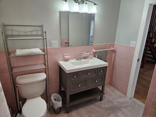 bathroom featuring tile walls, wainscoting, vanity, and toilet