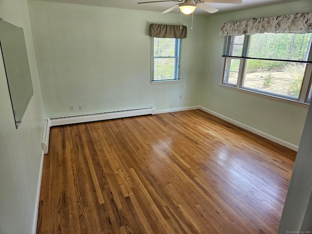 spare room featuring baseboards, a ceiling fan, wood finished floors, and a baseboard radiator