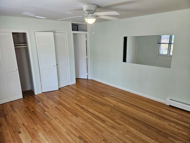 unfurnished bedroom featuring light wood-type flooring, baseboards, a baseboard radiator, two closets, and ceiling fan